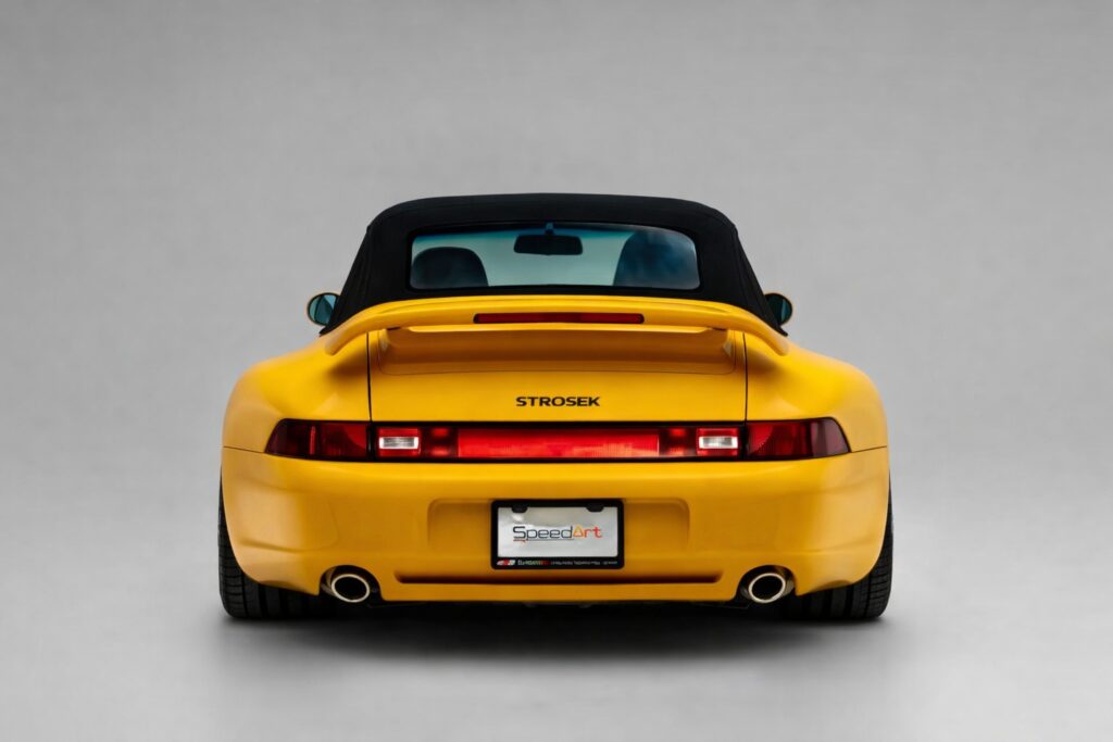 Rear view of a yellow 1995 Porsche 911 Strosek Cabriolet with black soft top