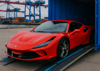 Red Ferrari 458 being loaded into a blue shipping container at a port highlighting global supercar logistics and delivery disruptions