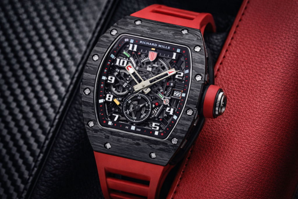 Luxury skeleton-style sports watch with a black tonneau case and red strap displayed on textured dark and red surfaces