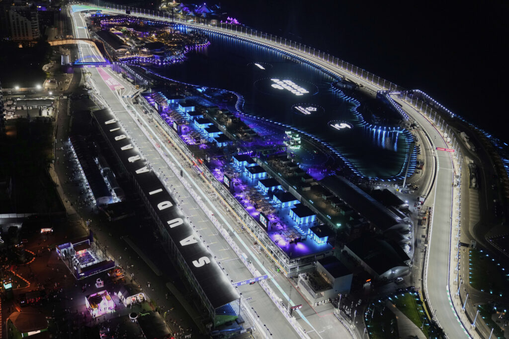 Aerial view of the Jeddah Corniche Circuit during a nighttime Formula 1 race with illuminated track and waterfront