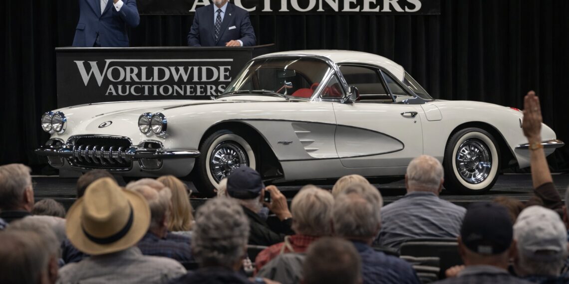 Classic white Chevrolet Corvette being auctioned on stage in front of a live audience at a luxury collector car auction