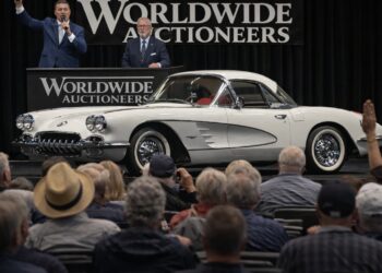Classic white Chevrolet Corvette being auctioned on stage in front of a live audience at a luxury collector car auction