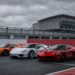 McLaren P1, Porsche 918 Spyder, and Ferrari LaFerrari lined up on a racetrack under an overcast sky