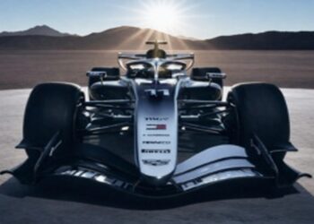 Front view of a Cadillac Formula 1 concept race car on a desert flat with mountains and sun rays in the background