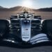 Front view of a Cadillac Formula 1 concept race car on a desert flat with mountains and sun rays in the background