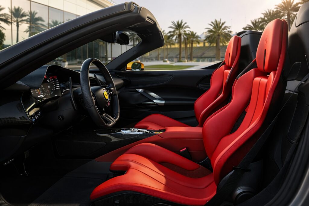 Ferrari convertible interior with red leather bucket seats, carbon fiber trim, and digital driver display