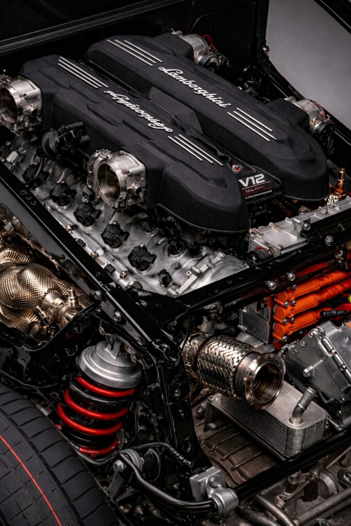 Close-up of a Lamborghini V12 engine bay with black covers, metallic components, and red performance accents