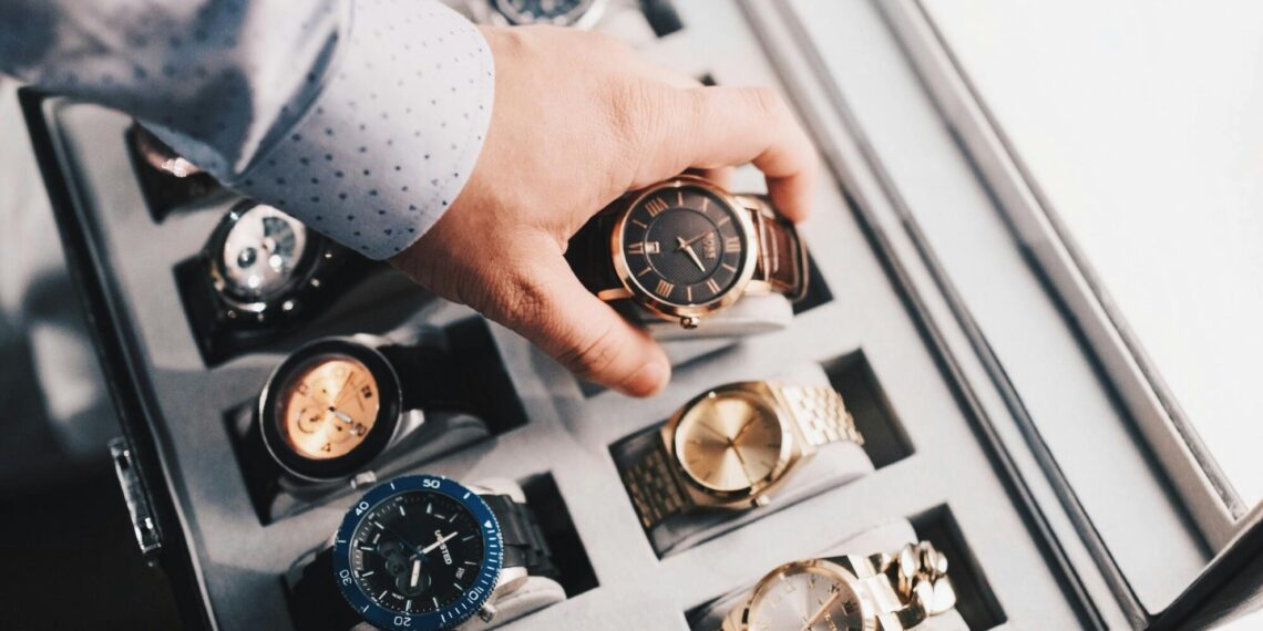 Luxury watch collection displayed in a premium storage case with a hand selecting a timepiece Title: