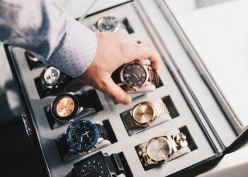 Luxury watch collection displayed in a premium storage case with a hand selecting a timepiece Title: