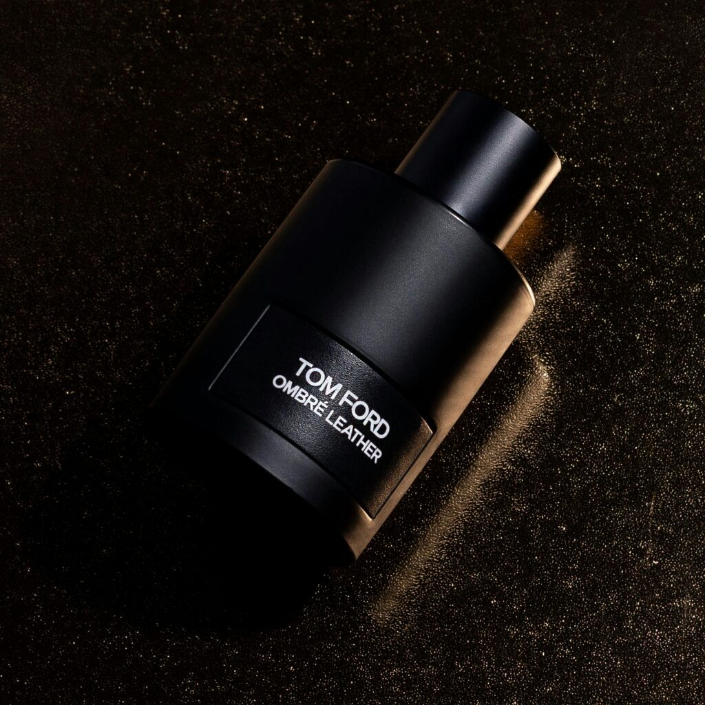 Black luxury fragrance bottle with minimalist design resting on a textured gold-speckled surface under dramatic lighting