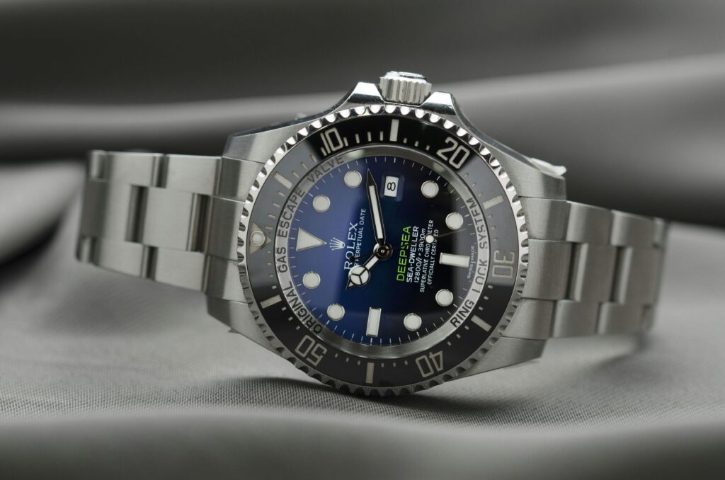Stainless steel luxury dive watch with blue dial and rotating bezel resting on a soft fabric surface
