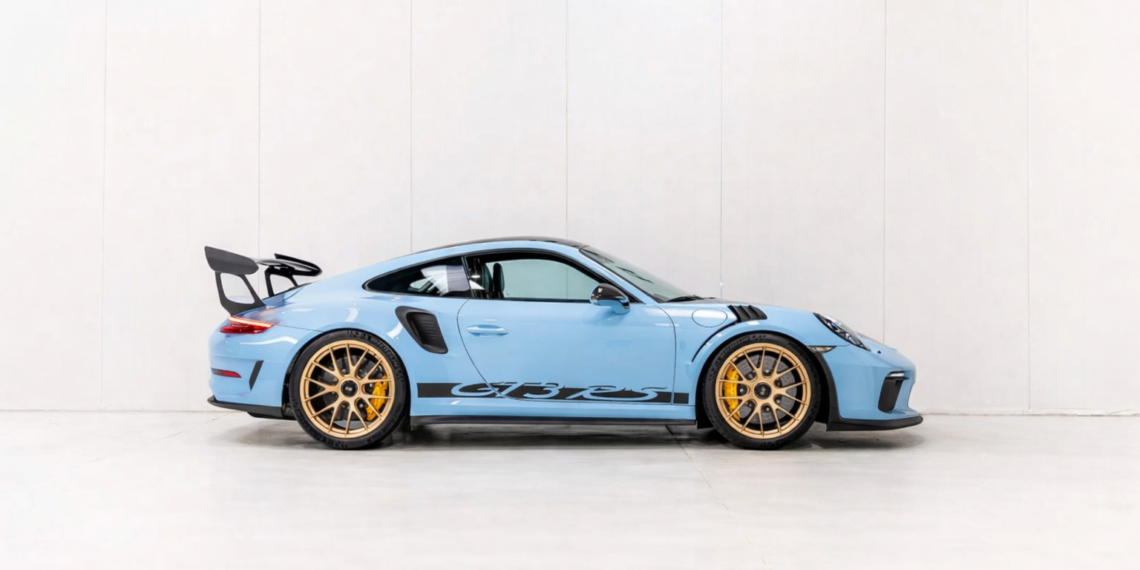 Blue Porsche 911 GT3 RS side profile in a clean studio setting with gold wheels and black aero accents