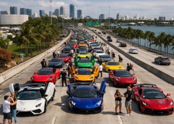 Large exotic car rally meet lined up on a Miami causeway with skyline and waterfront in the background