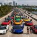 Large exotic car rally meet lined up on a Miami causeway with skyline and waterfront in the background