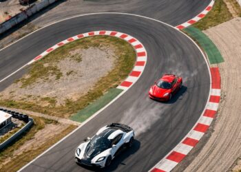 Aerial racetrack view of a hypercar pulling ahead of a supercar through a high-speed corner, illustrating performance differences between supercars and hypercars.