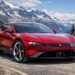 Red Ferrari EV 2026 parked on a mountain road with snow-capped peaks in the background, showcasing Maranello's first fully electric flagship design.