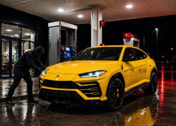 Yellow Lamborghini Urus at a gas station with a hooded person attempting to break into the vehicle at night. High-end suv theft