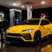 Yellow Lamborghini Urus at a gas station with a hooded person attempting to break into the vehicle at night. High-end suv theft