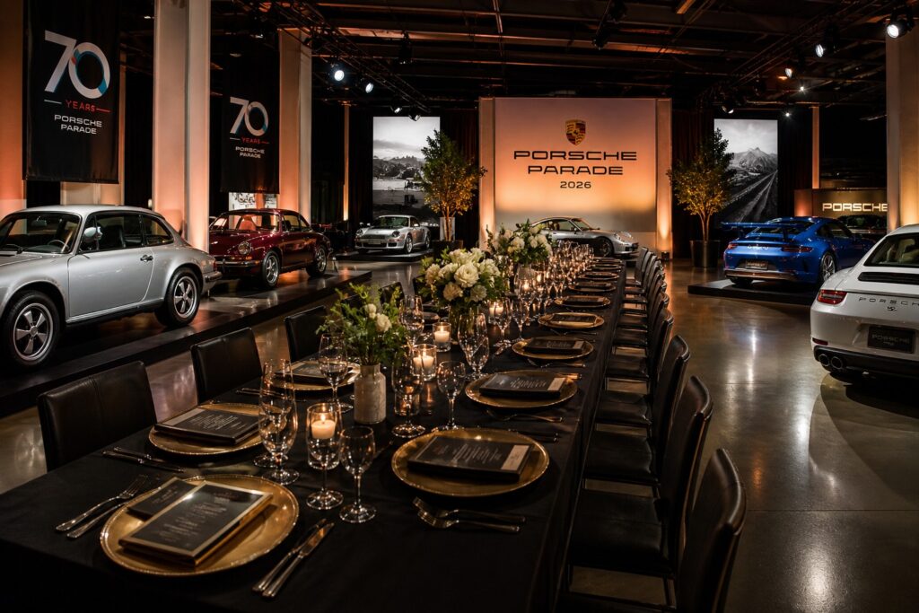 Porsche Parade 2026 luxury banquet surrounded by classic and modern Porsche 911 models in an upscale indoor event setting