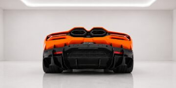 Orange Lamborghini Revuelto rear view with center exhaust outlets and carbon fiber diffuser in a white studio backdrop