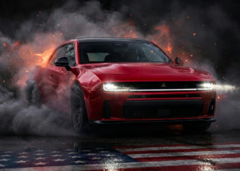 New Dodge Charger bursting through tire smoke with headlights blazing, symbolizing the comeback of American muscle