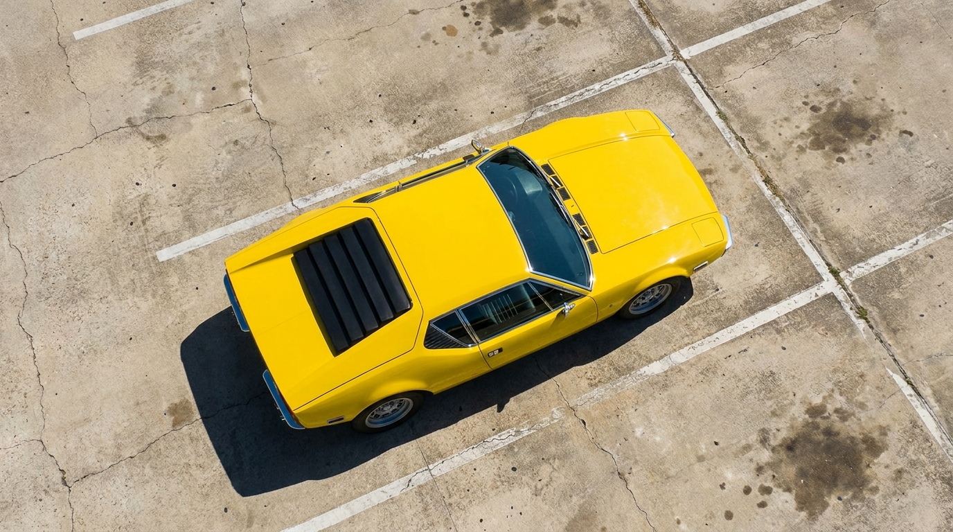 Overhead top-down view of a yellow De Tomaso Pantera on a concrete pad