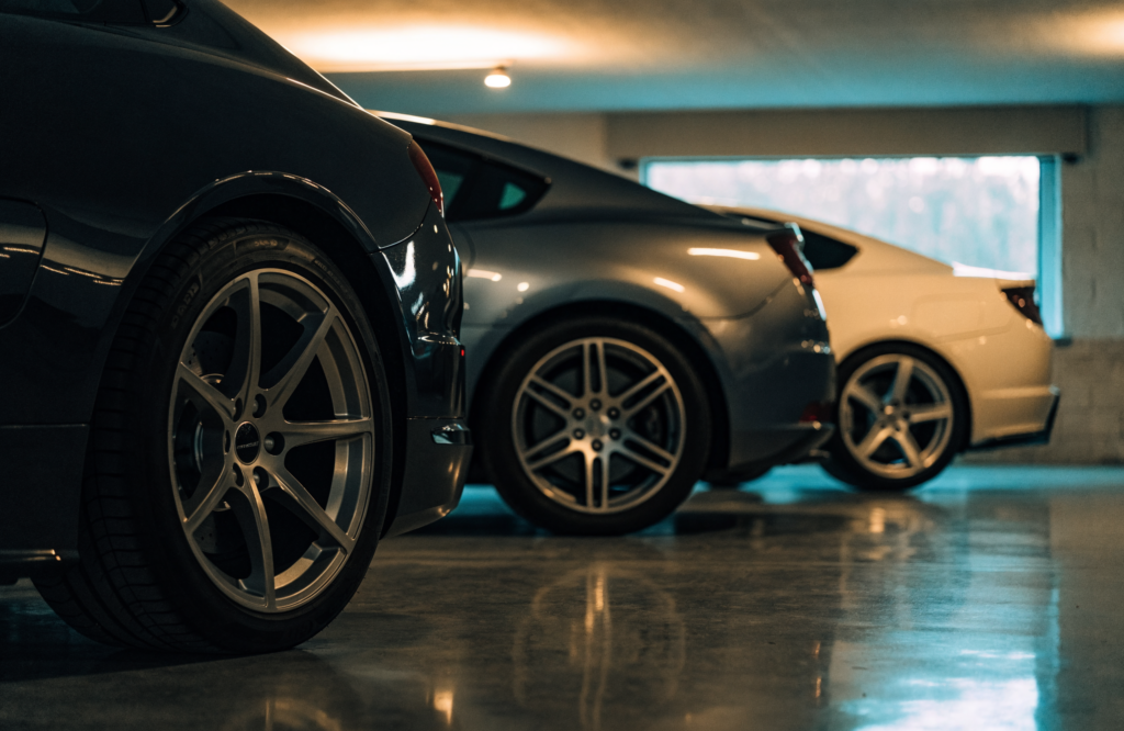 Three anonymous sports cars parked in a private garage, illustrating the kind of exotic cars under 150k covered in this guide