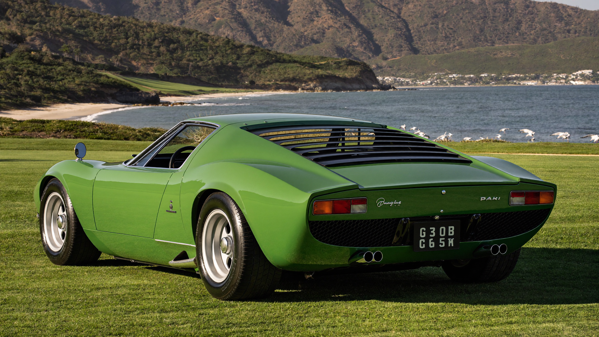 Verde green Lamborghini Miura P400 rear view with slatted louvres overlooking Carmel Bay at Pebble Beach