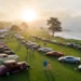 Wide view of collector cars and modern supercars lined up on a coastal California fairway during Monterey Car Week 2026