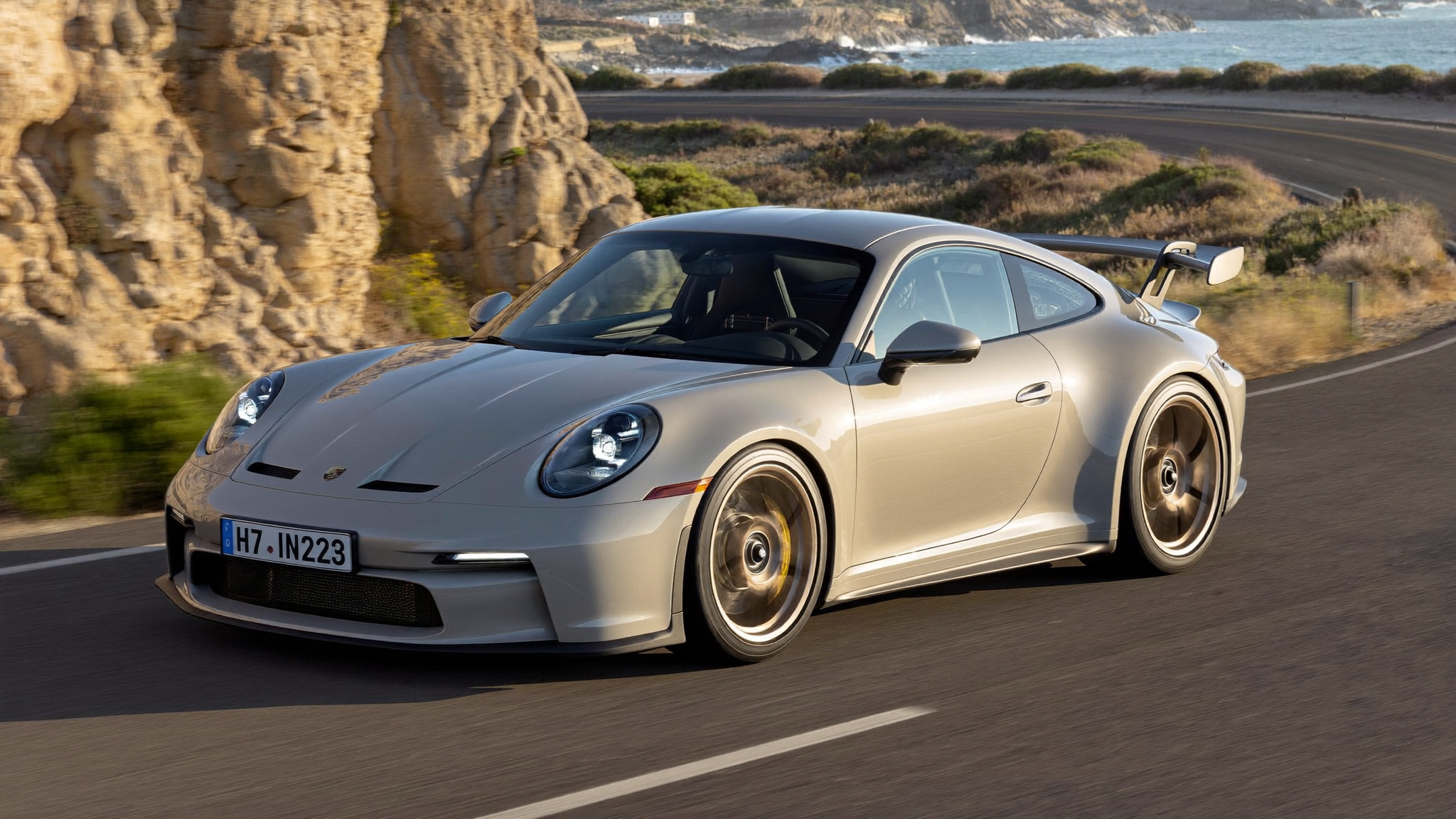 Porsche 911 GT3 992 generation driving a coastal canyon road at golden hour — one of the hottest cars in the 2026 exotic vehicle marketplace