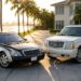 Two icons of hip-hop luxury cars: a two-tone 2004 Maybach 57 and a pearl-white 2004 Cadillac Escalade on a Miami waterfront drive