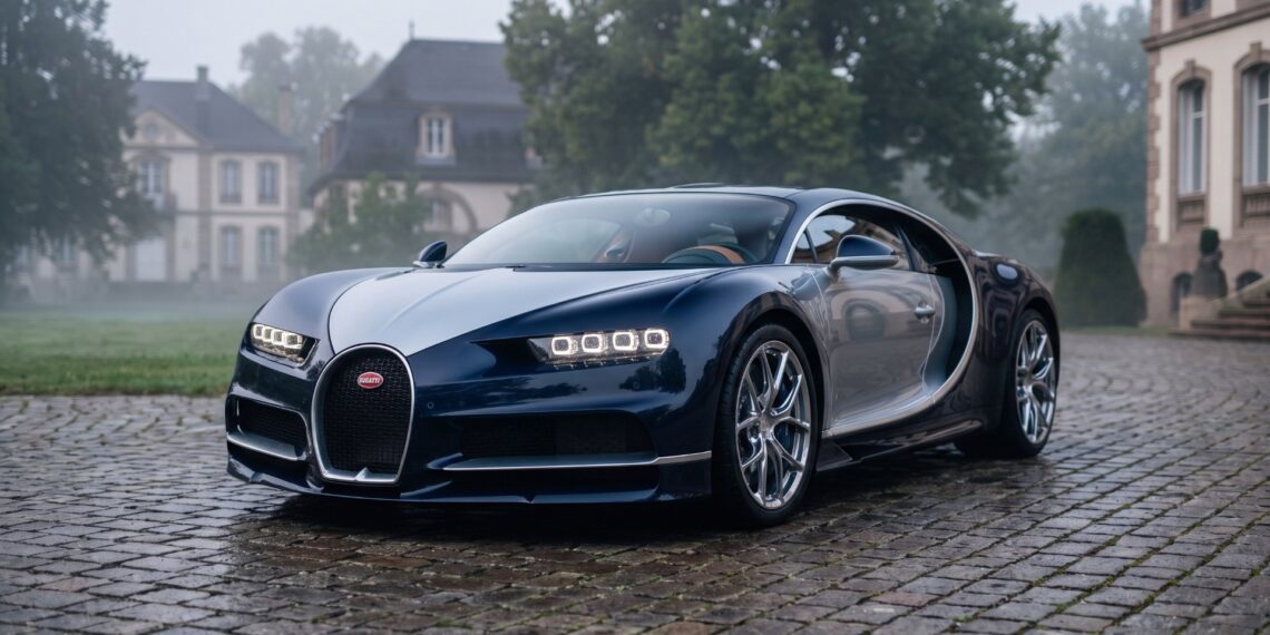Two-tone blue Bugatti Chiron parked on wet cobblestones in front of a French château at dawn. AI-generated editorial visualization, not a photograph.