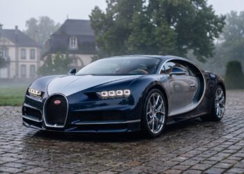 Two-tone blue Bugatti Chiron parked on wet cobblestones in front of a French château at dawn. AI-generated editorial visualization, not a photograph.