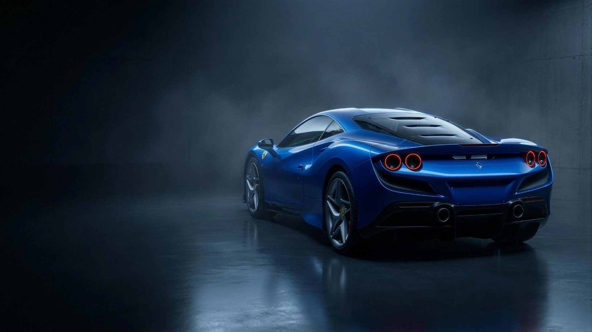 Blue Ferrari F8 Tributo from the rear three-quarter angle in a dark concrete studio, red ring taillights glowing