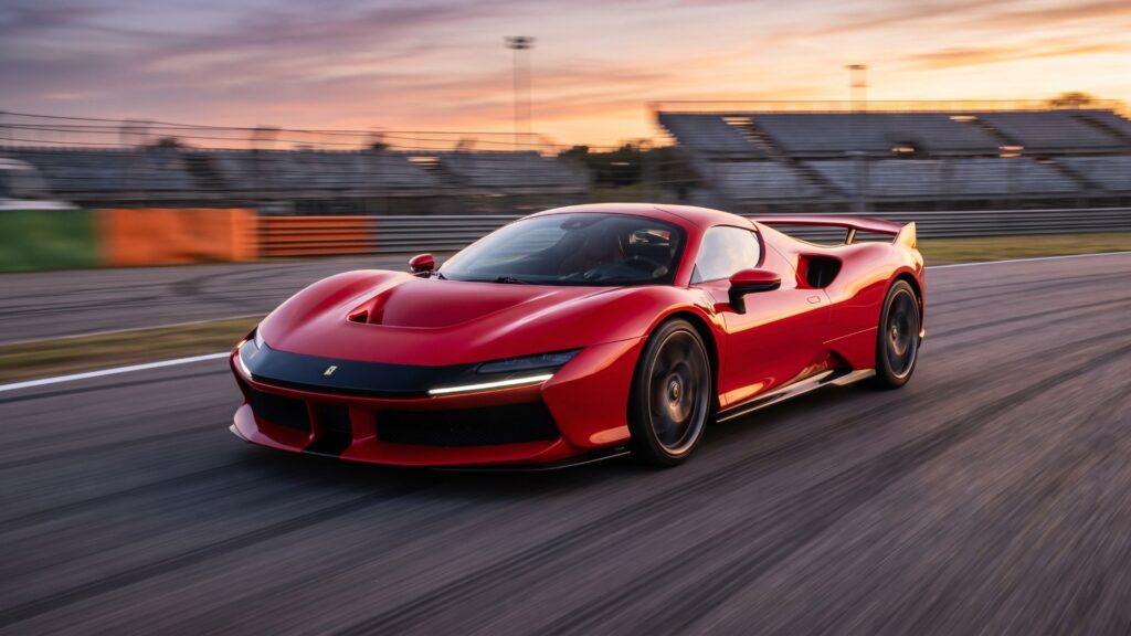 Red Ferrari F80 hypercar at speed on a racing circuit at sunset with empty grandstands behind