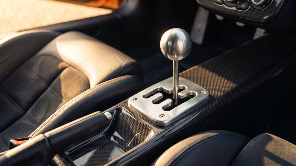Polished metal gated six-speed manual shifter on a carbon-fibre centre tunnel between black leather supercar seats