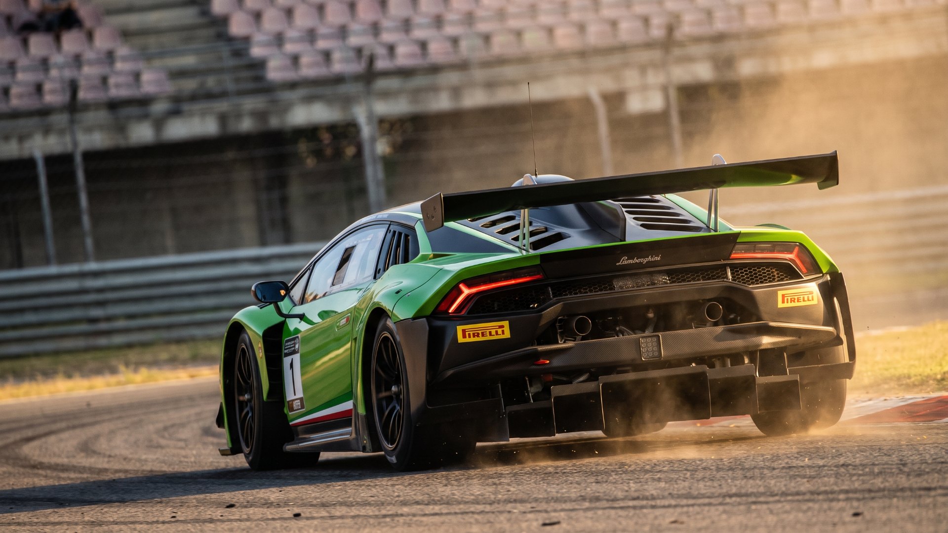 Rear three-quarter view of a Lamborghini GT3 race car on corner exit showing swan-neck rear wing and diffuser