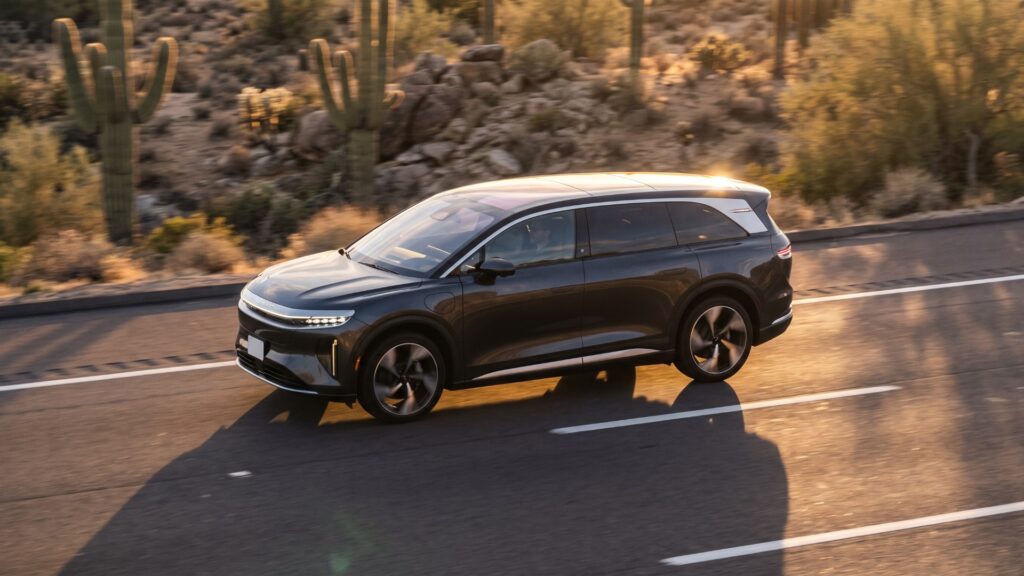 Dark grey Lucid Gravity electric SUV driving on a desert highway at golden hour
