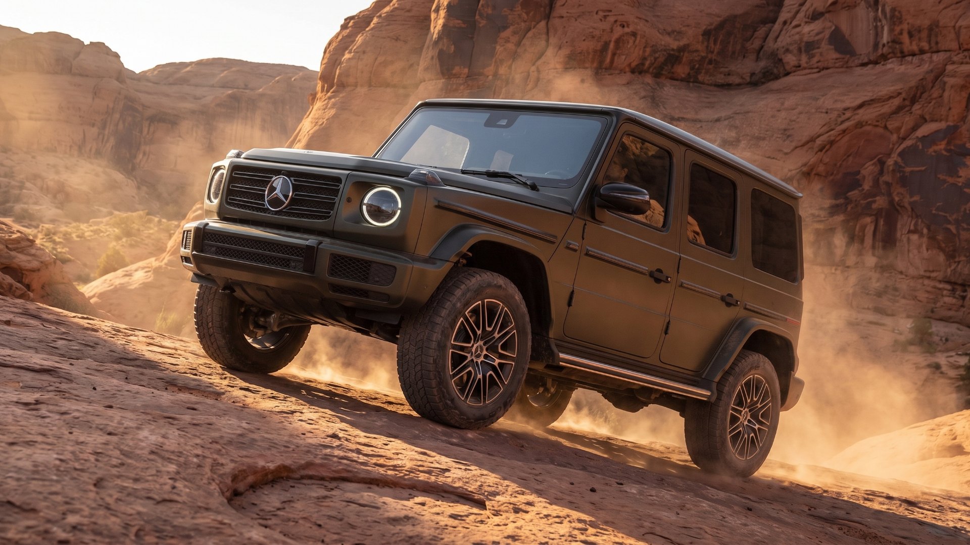 Dark olive electric Mercedes-Benz G-Class climbing a steep red-rock slab in a dusty desert canyon