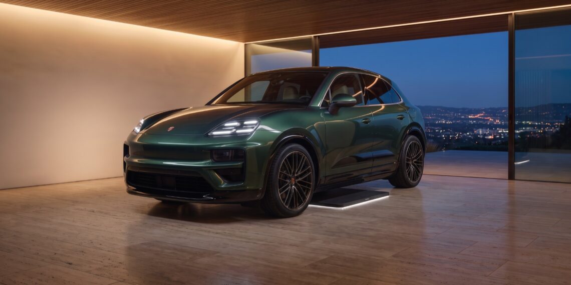 Green Porsche Cayenne Electric parked over a wireless charging floor plate in a hillside home garage at night