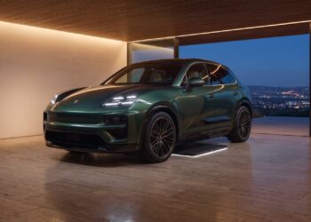 Green Porsche Cayenne Electric parked over a wireless charging floor plate in a hillside home garage at night