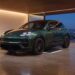 Green Porsche Cayenne Electric parked over a wireless charging floor plate in a hillside home garage at night