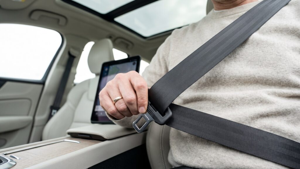 Passenger fastening the Volvo EX60 multi-adaptive seat belt, an example of new car safety technology