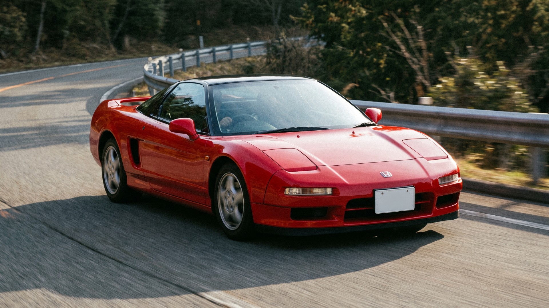 Red first-generation Honda NSX with a black roof cornering on a mountain road