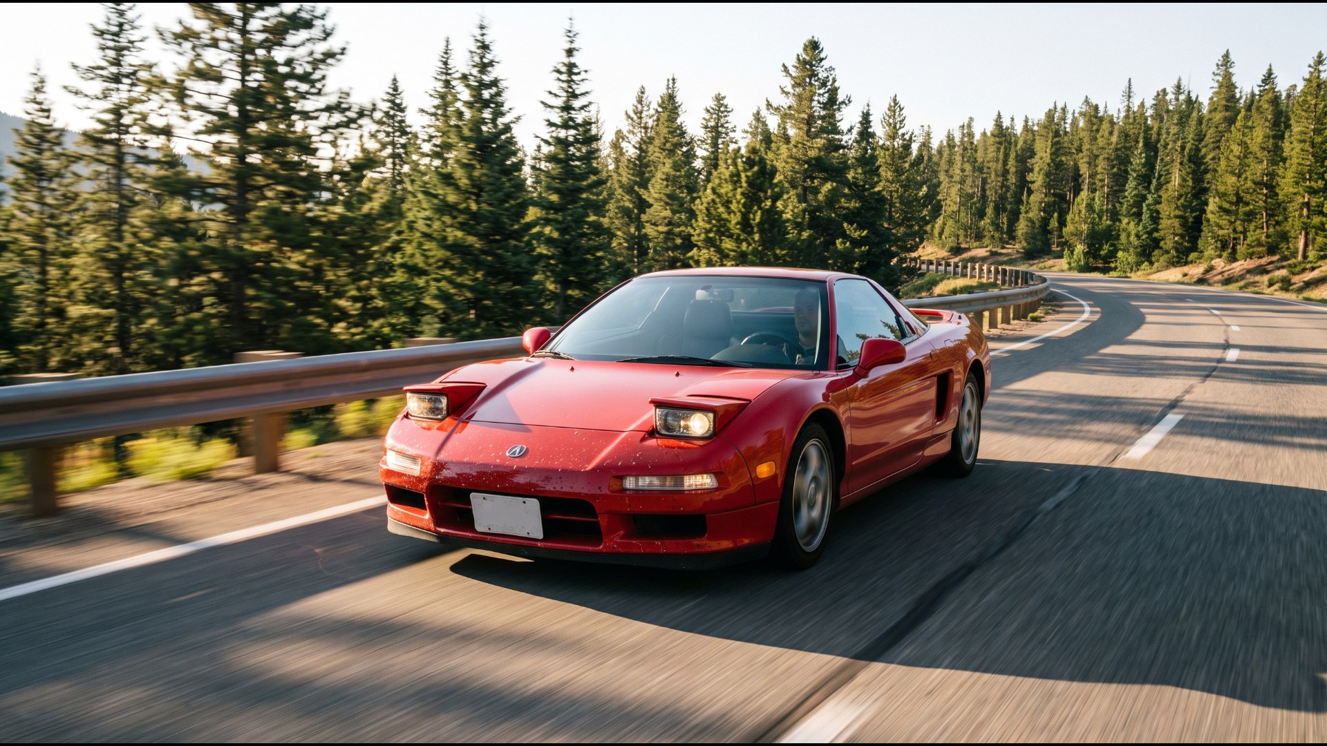 Red first-generation Acura NSX cornering on a mountain road lined with pines