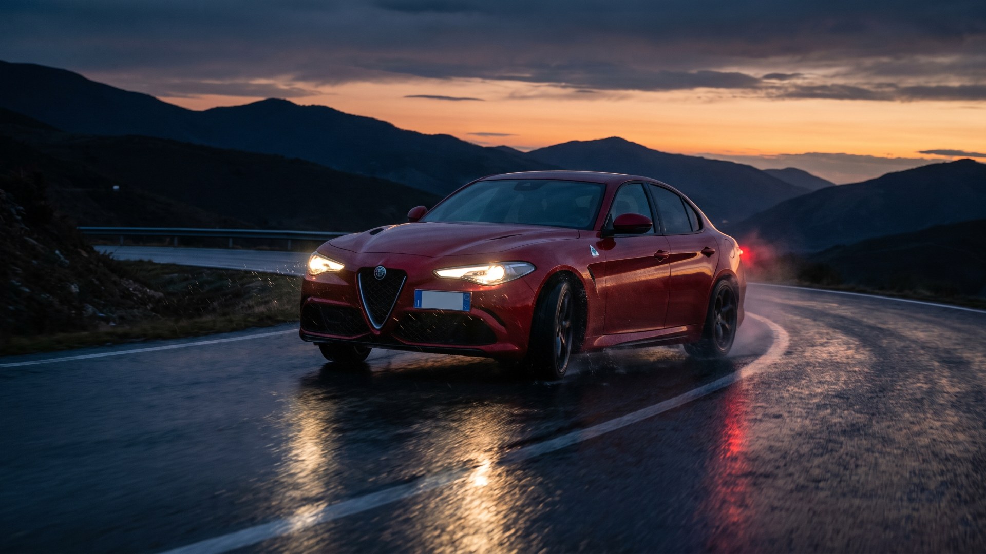 Red Alfa Romeo Giulia Quadrifoglio braking on a wet mountain road at dusk