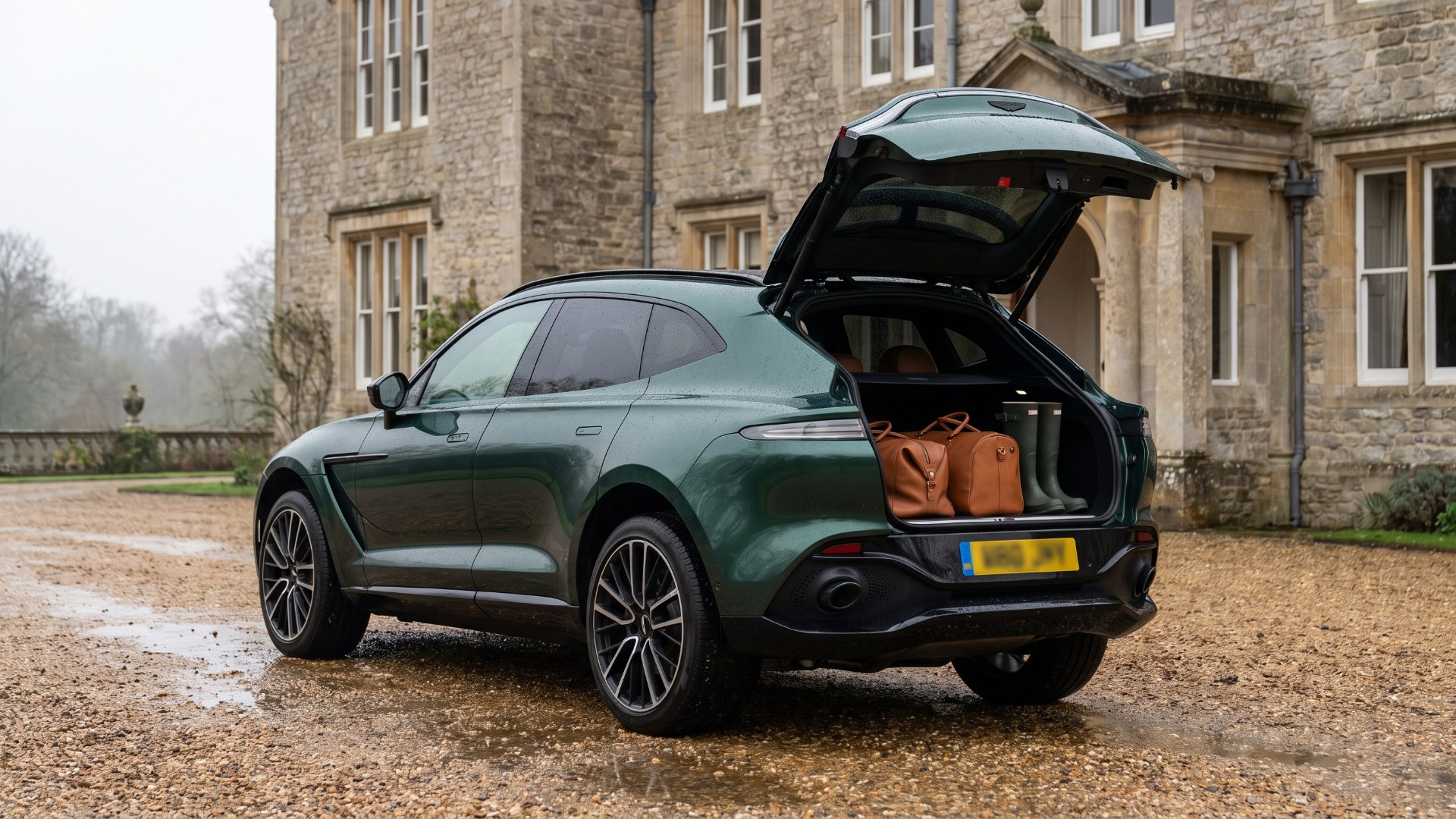 Green Aston Martin DBX with luggage in its open cargo area outside a country house