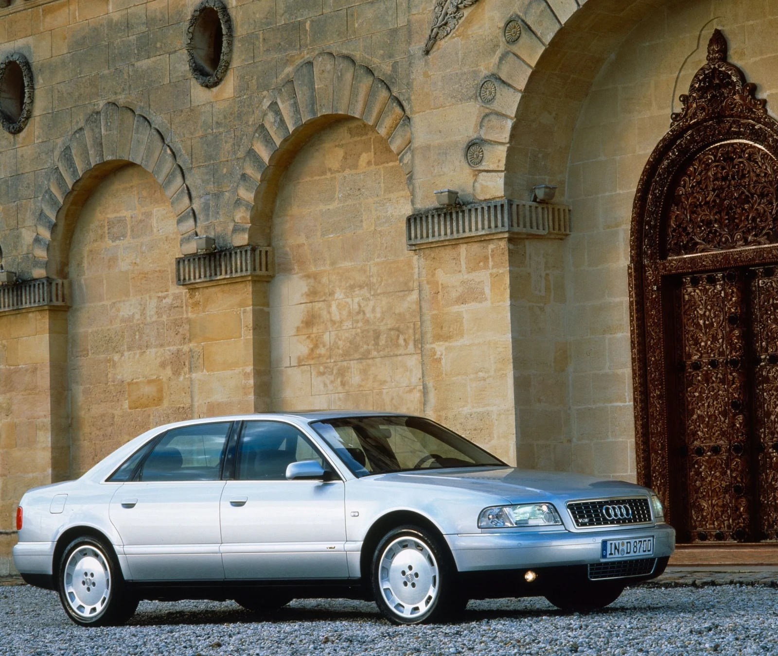 Silver first-generation Audi A8 W12 parked in front of stone arches
