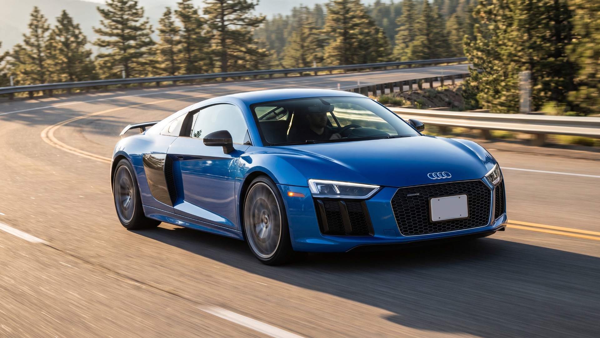 Blue Audi R8 V10 Plus coupe driving on a mountain road