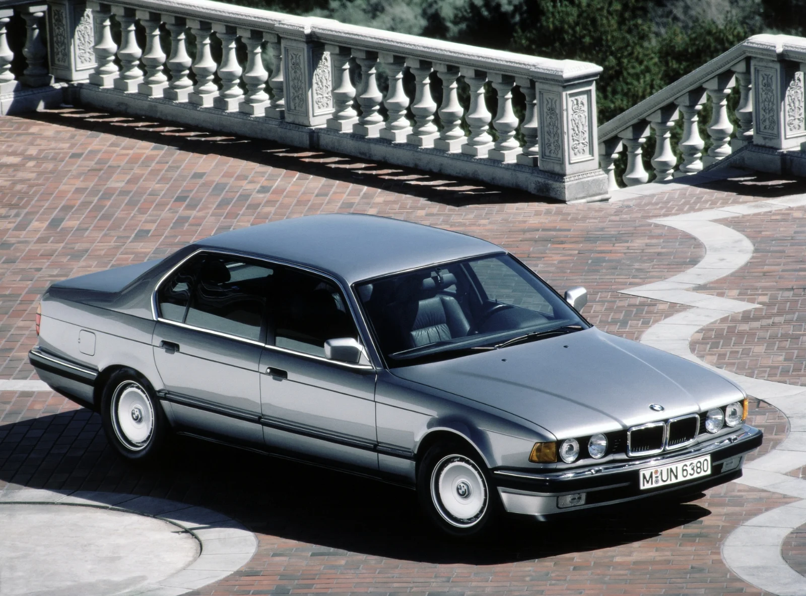 Silver BMW 7 Series E32 long-wheelbase sedan on a stone terrace
